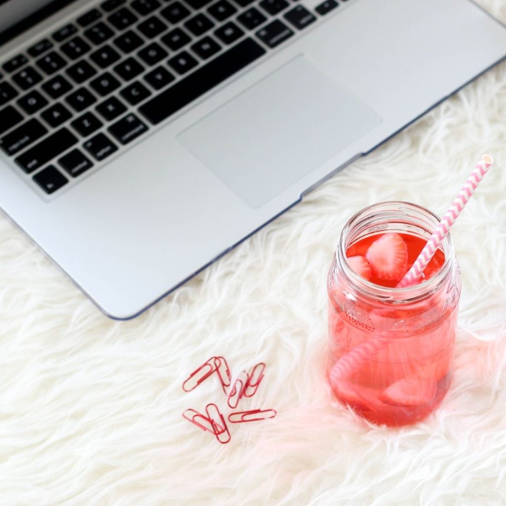 A laptop next to a berry drink to illustrate learning how to write website copy and researching your audience. 